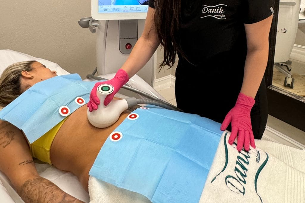 Specialist Wearing Black Unifrom And Pink Gloves Applying UltraShape Treatment For Body Contour On A Woman Patient Abs Using UltraShape Equipment