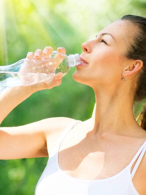 Woman drinking water outdoors, enjoying the benefits of the HCG Diet from Danik MedSpa.